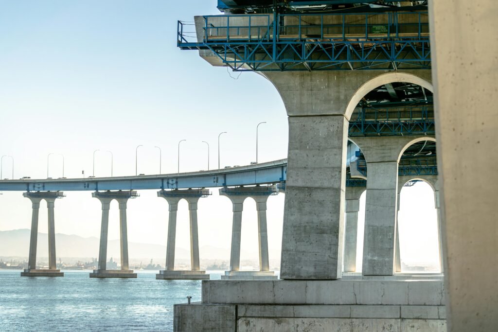 Elegant bridge structure over water in San Diego with cityscape in the background.